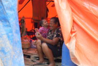 Seorang ibu dan anak memanfaatkan layanan telekomunikasi pascabencana di Sumatra.